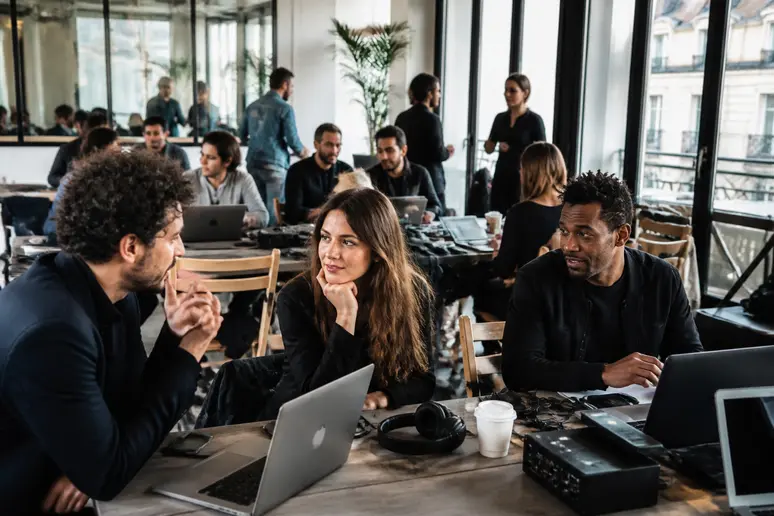 Professionnels de la musique échangeant sur irmawork dans un espace de coworking moderne à Paris, favorisant les connexions.