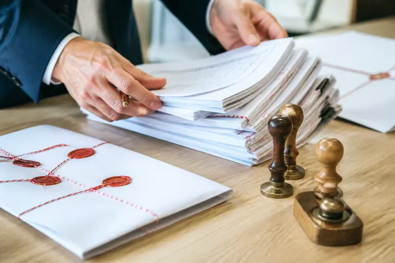 Mains triant des actes notariés et des documents juridiques lors d'une liquidation