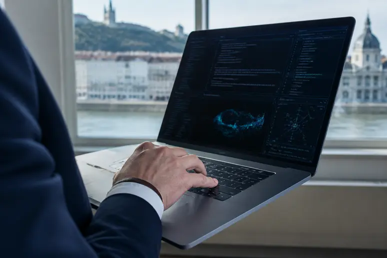 Compétences CISSP : une main manipule un ordinateur portable dans un bureau lyonnais.