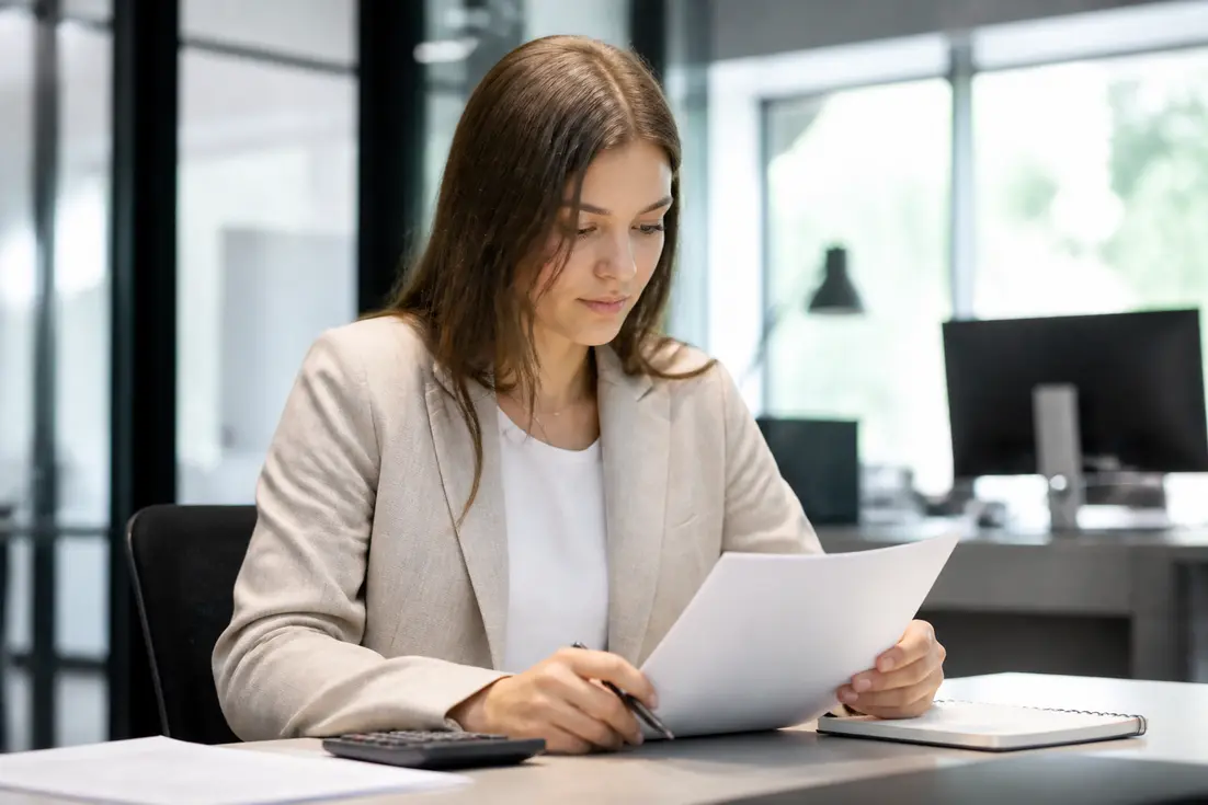 Calcul de la gratification stagiaire au réel en 2026 : une jeune femme au bureau examine des documents financiers.