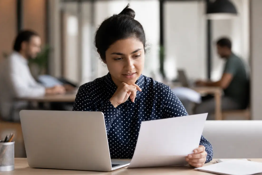 Jeune femme consultant un formulaire de remboursement imagine r dans un espace de coworking.