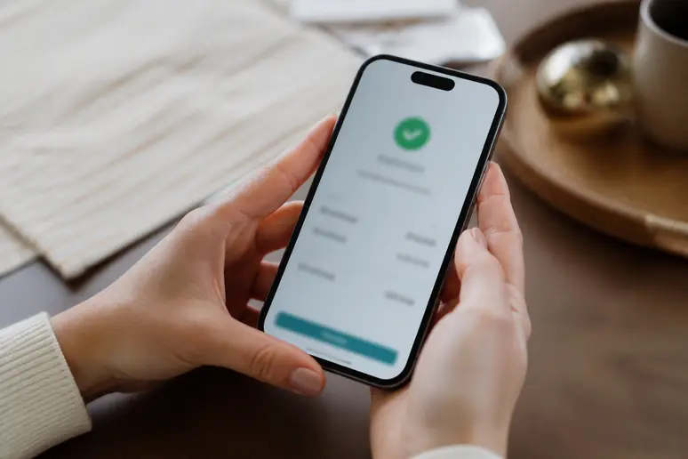 Mains tenant un smartphone affichant un virement bancaire récent reçu.