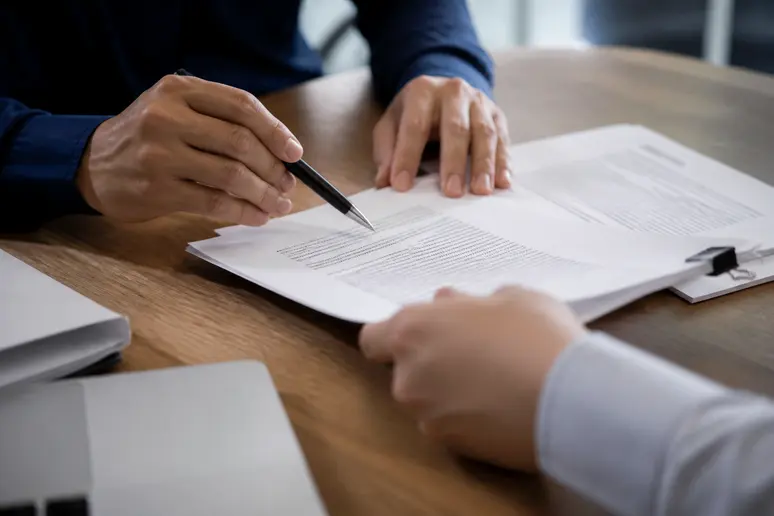 Mains analysant les clauses d'un contrat pour bien choisir son assurance entreprise.