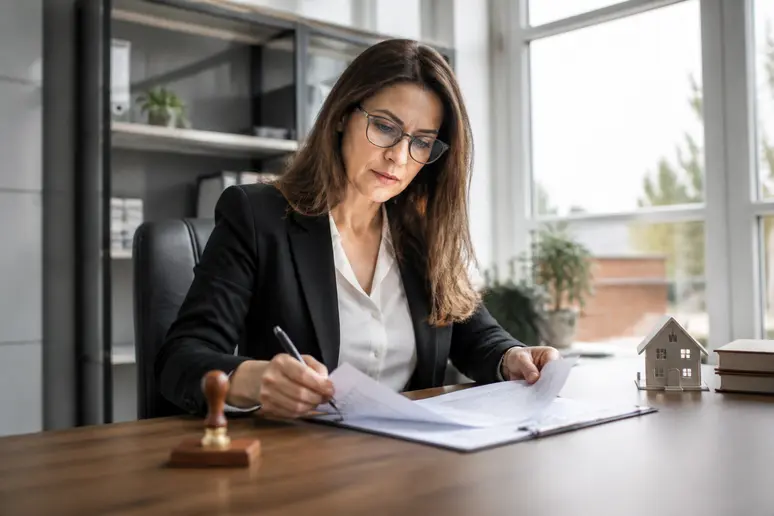 Notaire analysant un compromis de vente immobilière dans son bureau lumineux.