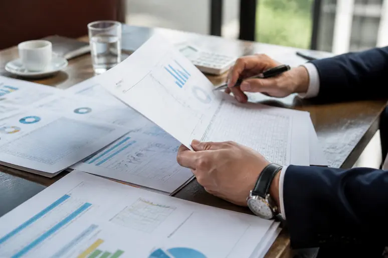 Un investisseur analyse un business plan et des prévisions financières lors d'un comité de sélection