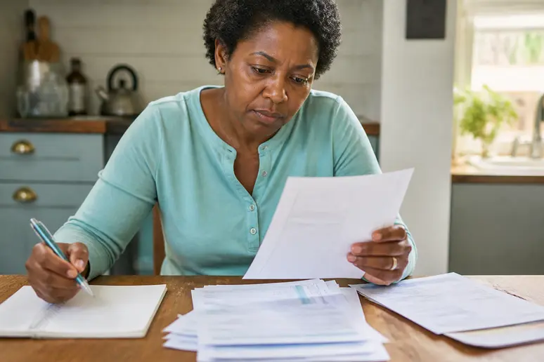 Personne consultant des relevés bancaires sur une table en bois pour analyser son budget.